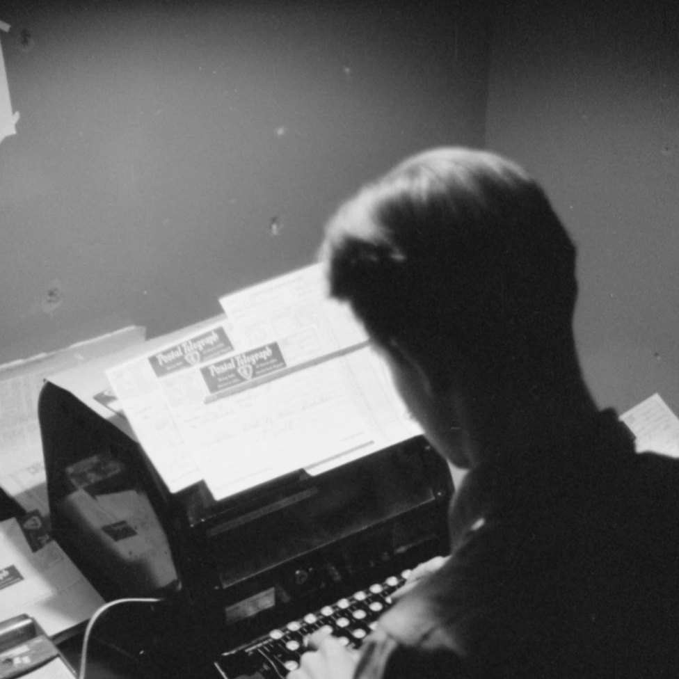 Black-and-white photograph of a person typing at a typewriter.
